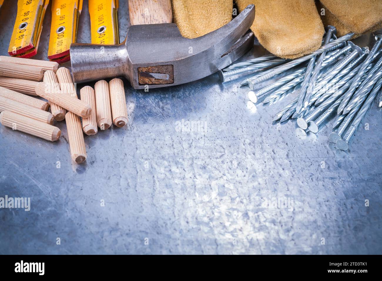Claw hammer leather safety gloves wood metre construction nails and dowels on scratched metallic background maintenance concept Stock Photo