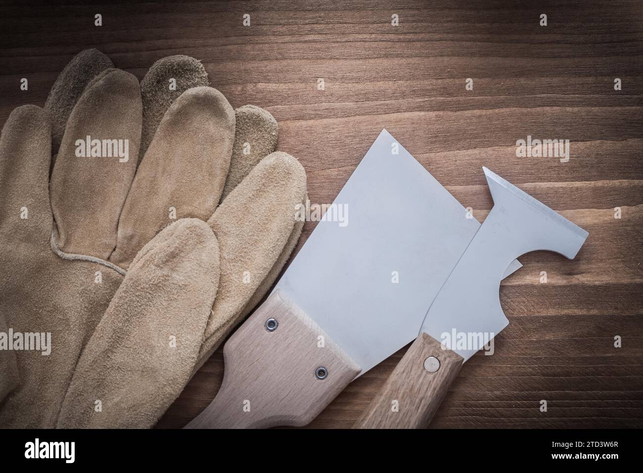 Leather safety gloves and shiny building filler on a wooden board Stock Photo