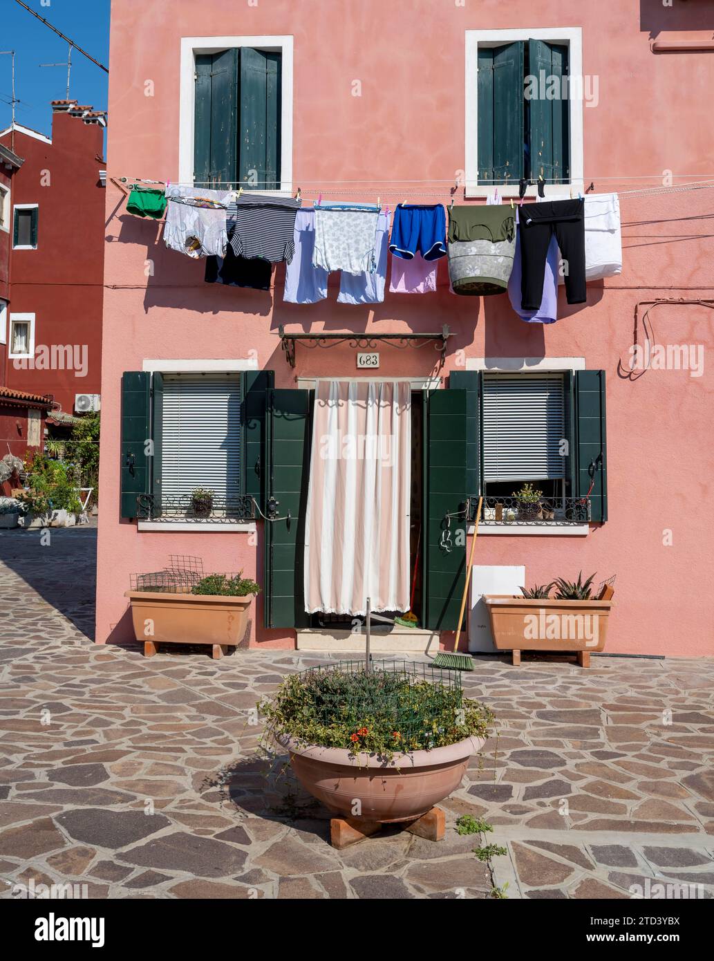 Pink house facade with clothesline, windows and front door, colourful houses, alleys on the island of Burano, Venice, Veneto, Italy Stock Photo