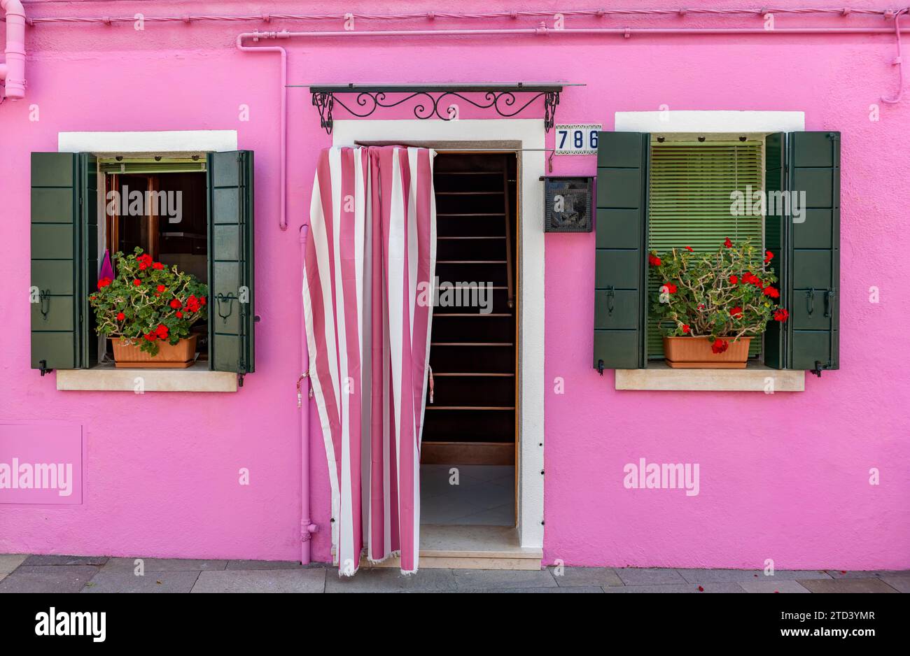 Pink house facade with entrance door and windows with flowers, colourful houses on the island of Burano, Venice, Veneto, Italy Stock Photo