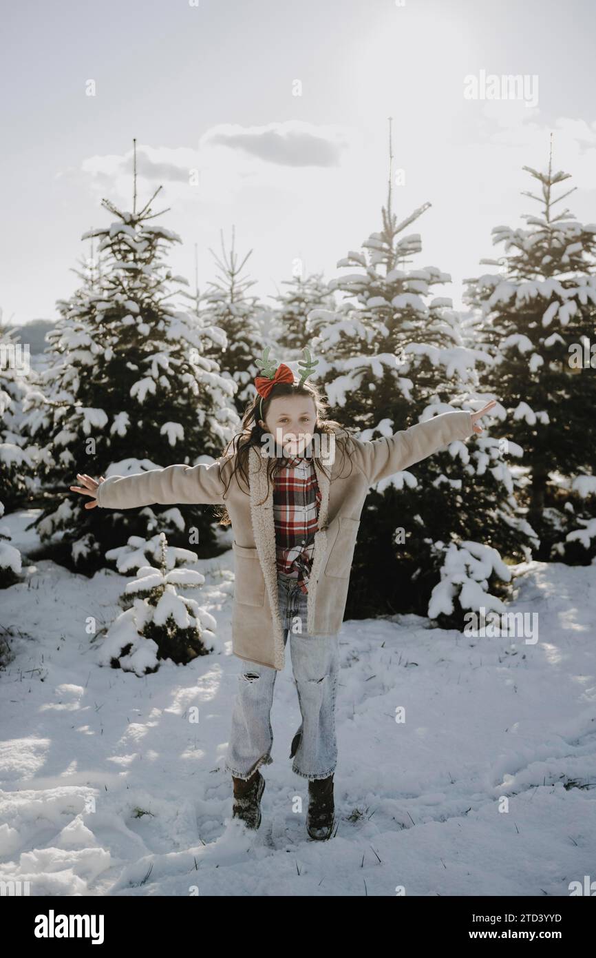 Girl in a winter coat in front of snow-covered fir trees Stock Photo