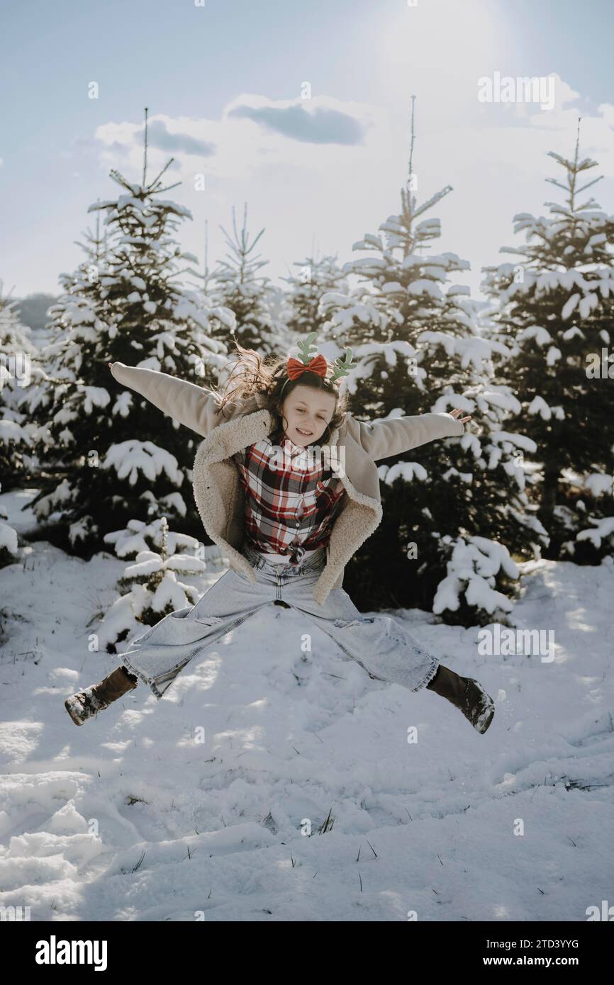 Girl in a winter coat in front of snow-covered fir trees Stock Photo