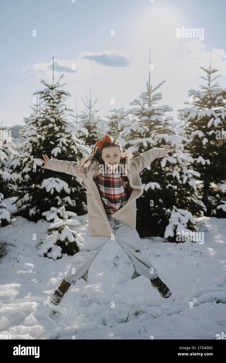 Girl in a winter coat in front of snow-covered fir trees Stock Photo