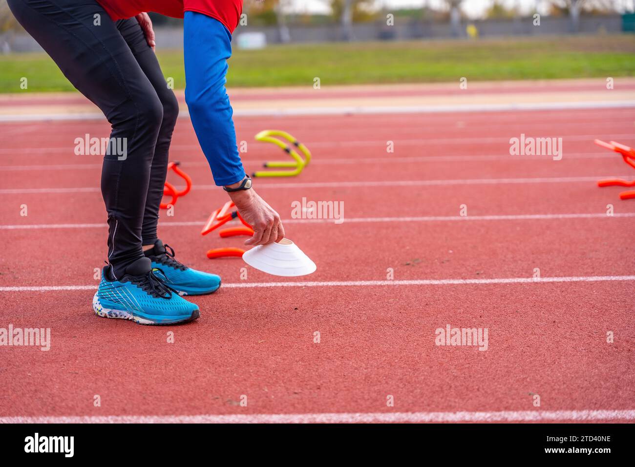 Lower part of an unrecognizable mature man preparing an athletic track with training elements Stock Photo