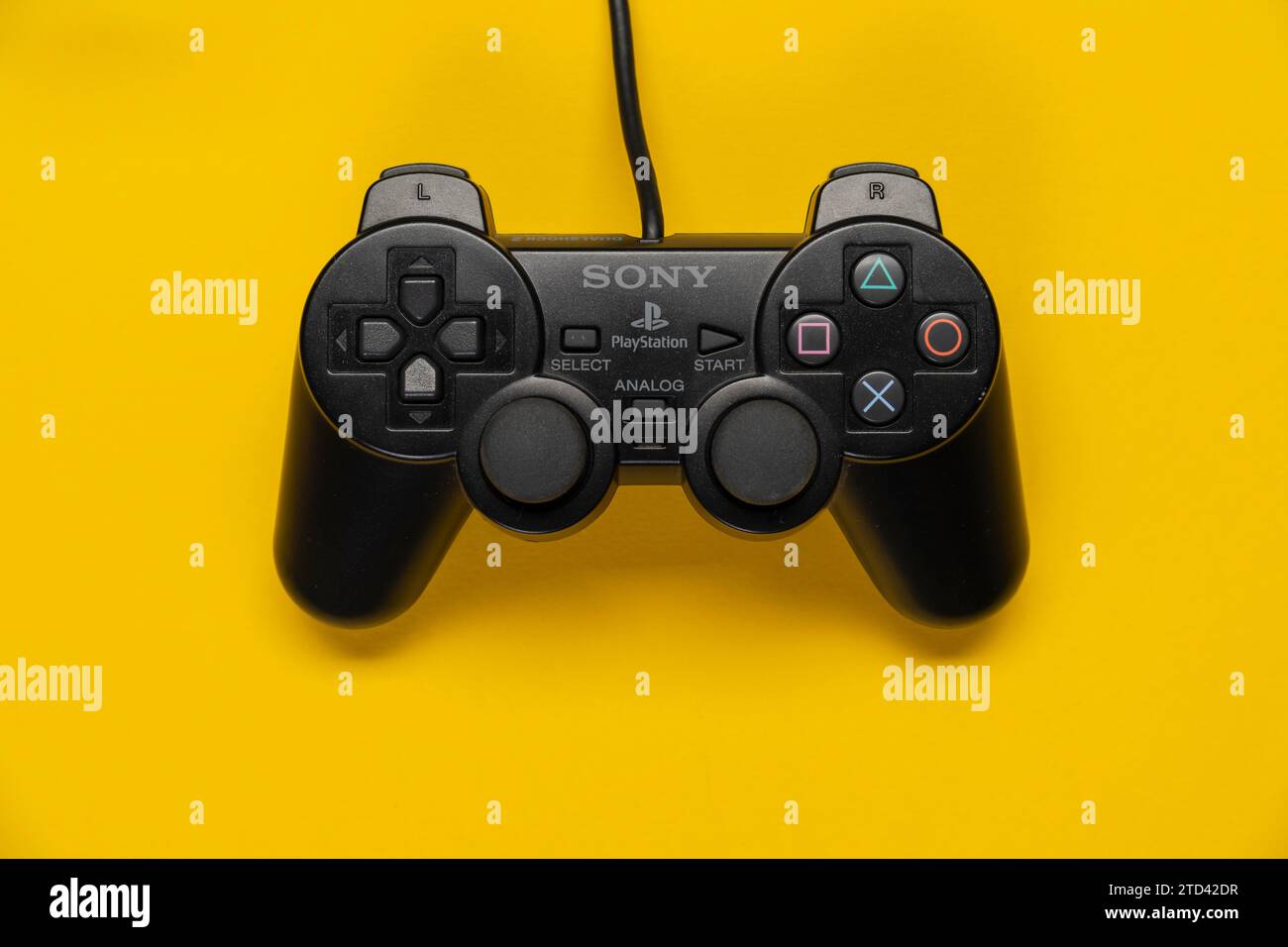 Controller of the PS2 Playstation game console from Sony in front of a monochrome yellow background, top view Stock Photo