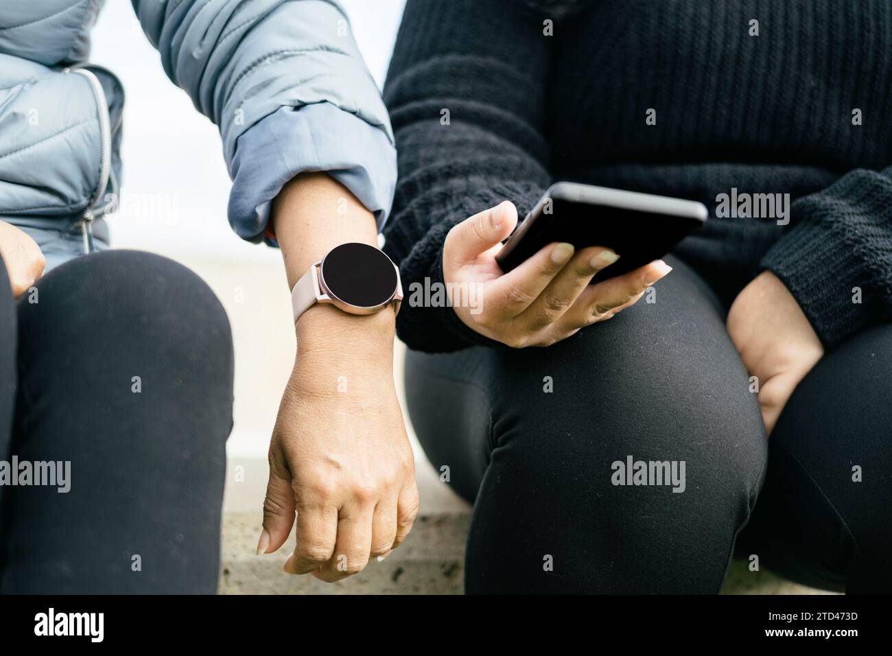Two beautiful Latina women are proudly displaying their new smartwatch and smartphone. These Hispanic ladies are definitely keeping up with the Stock Photo