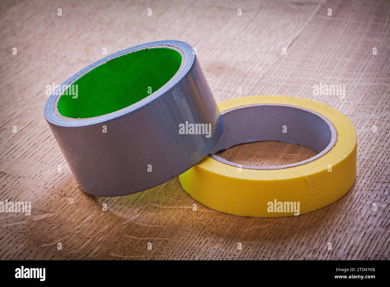 Yellow and blue rolls of adhesive tape on vintage brown wooden board construction concept Stock Photo