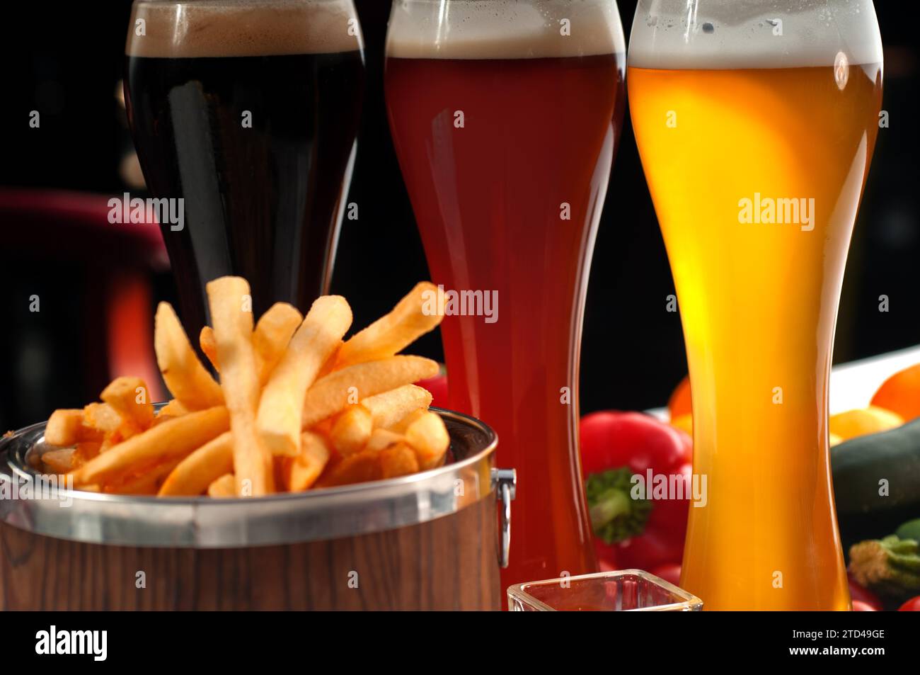 Fresh french fries on a wood bucket with selection of beers and fresh vegetables on background, food photography Stock Photo