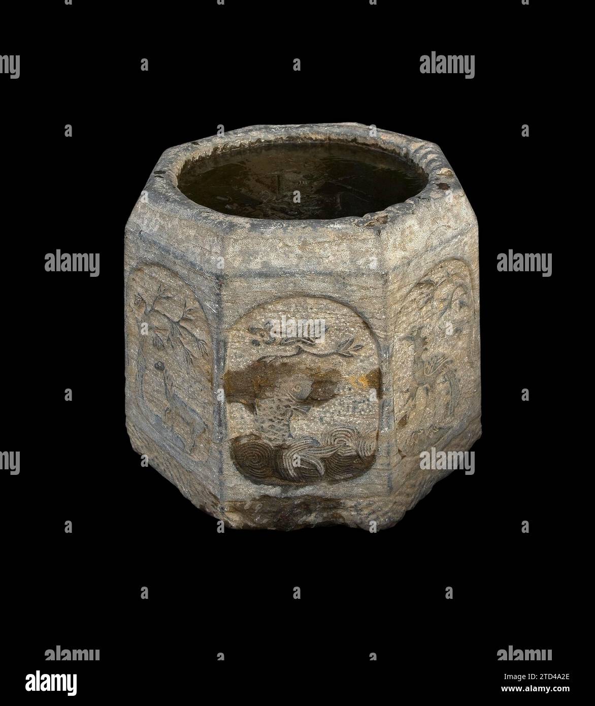 Ancient stone bucket finely carved with iced water over black backgroungd Stock Photo
