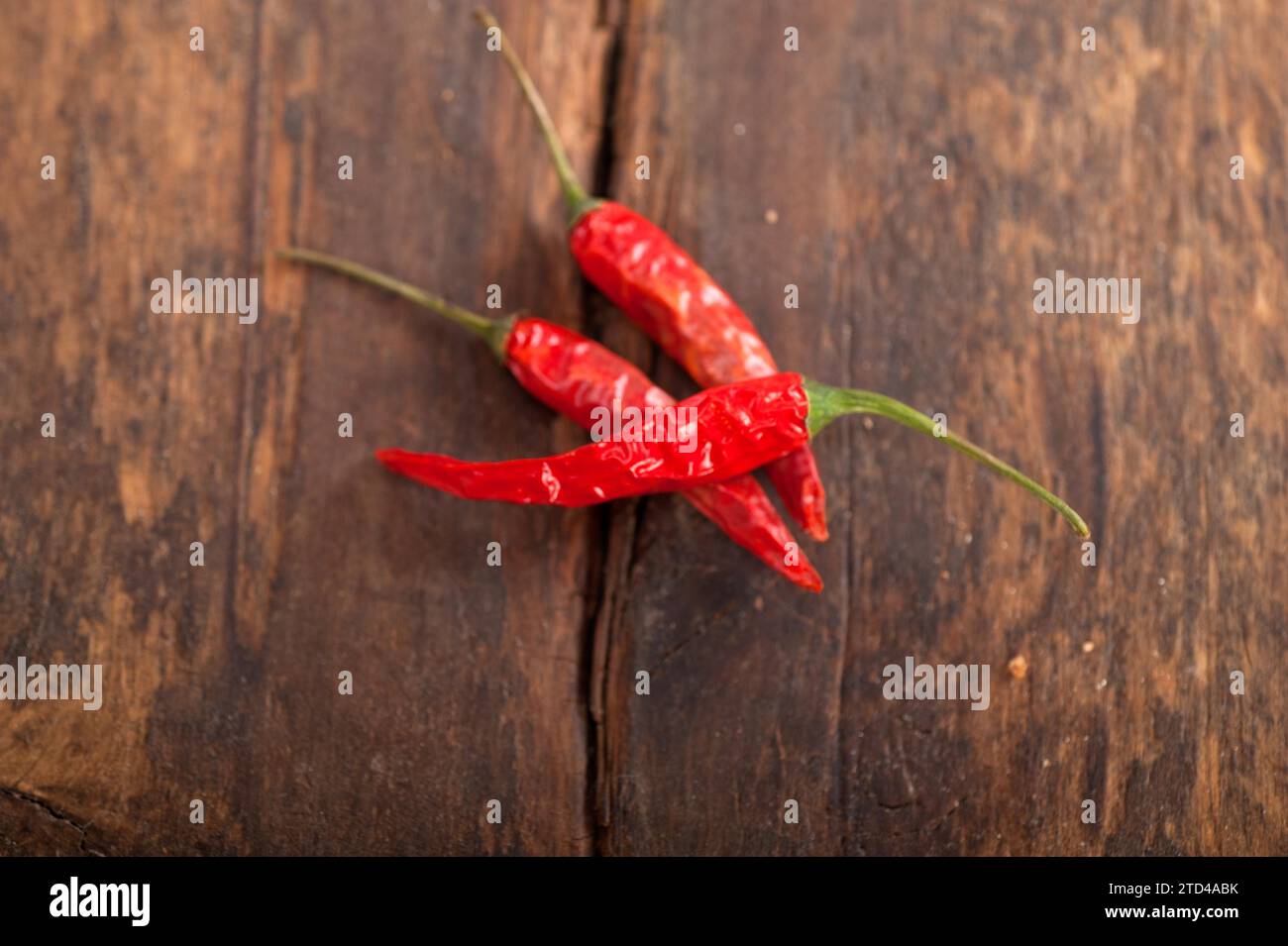 Dry red chili peppers over old wood table Stock Photo - Alamy