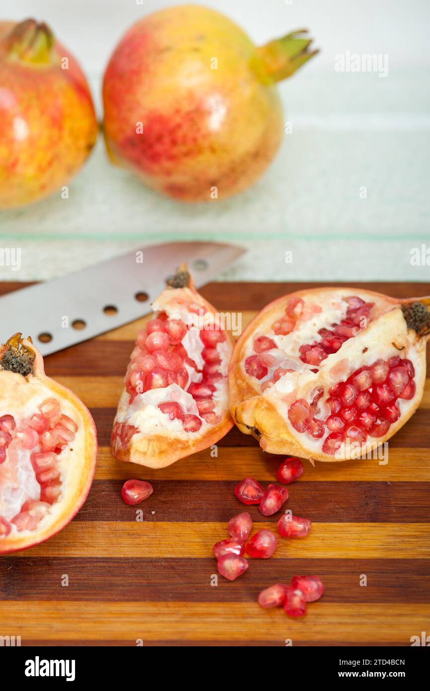 Fresh pomegranate fruit over wood cutting board with knife, food photography Stock Photo