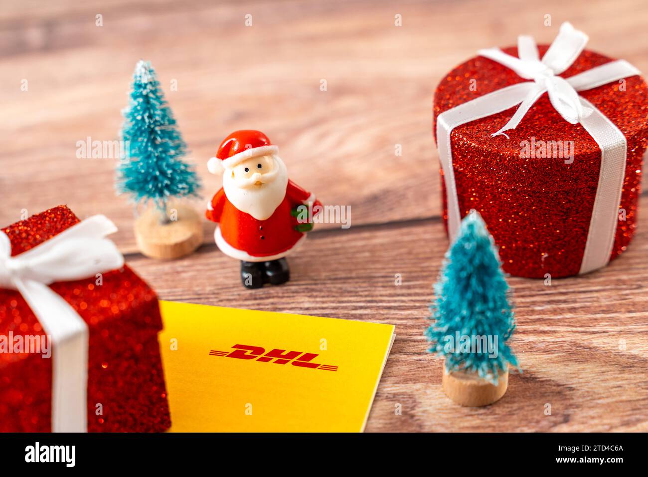 Augsburg, Bavaria, Germany - December 15, 2023: DHL parcel and parcel shipping label next to decoration for Christmas, a red wrapped gift *** DHL Paket und Päckchen Versandschein neben Dekoration zu Weihnachten, einem roten verpackten Geschenk Stock Photo