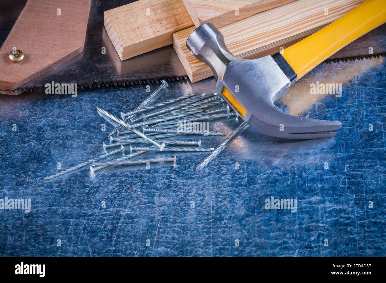 Close up image of metal nails hammer wooden bricks hacksaw on scratched metallic surface construction concept Stock Photo