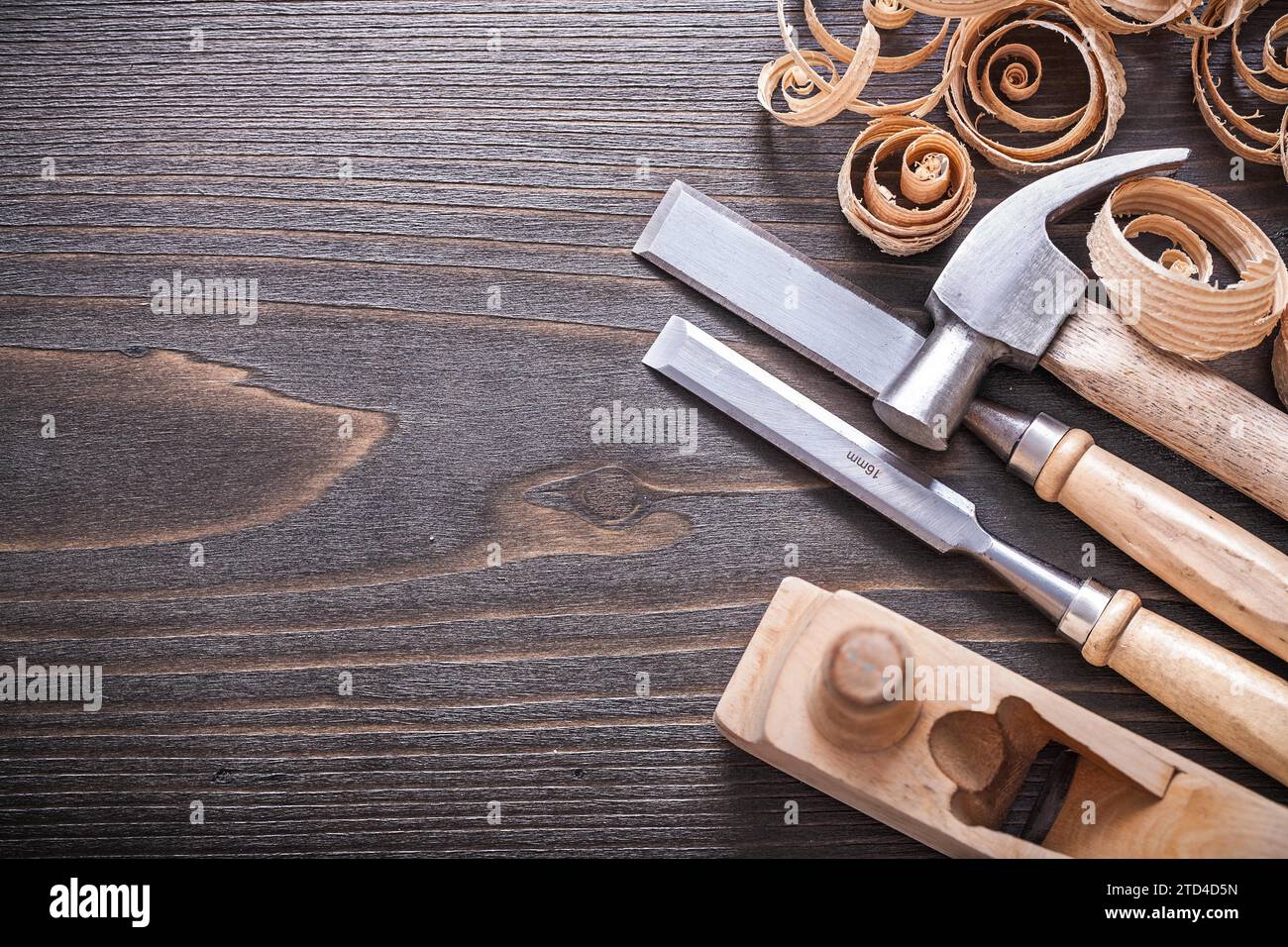 Planner claw hammer metal fixed chisel and wooden curled shavings on vintage wooden board building concept Stock Photo