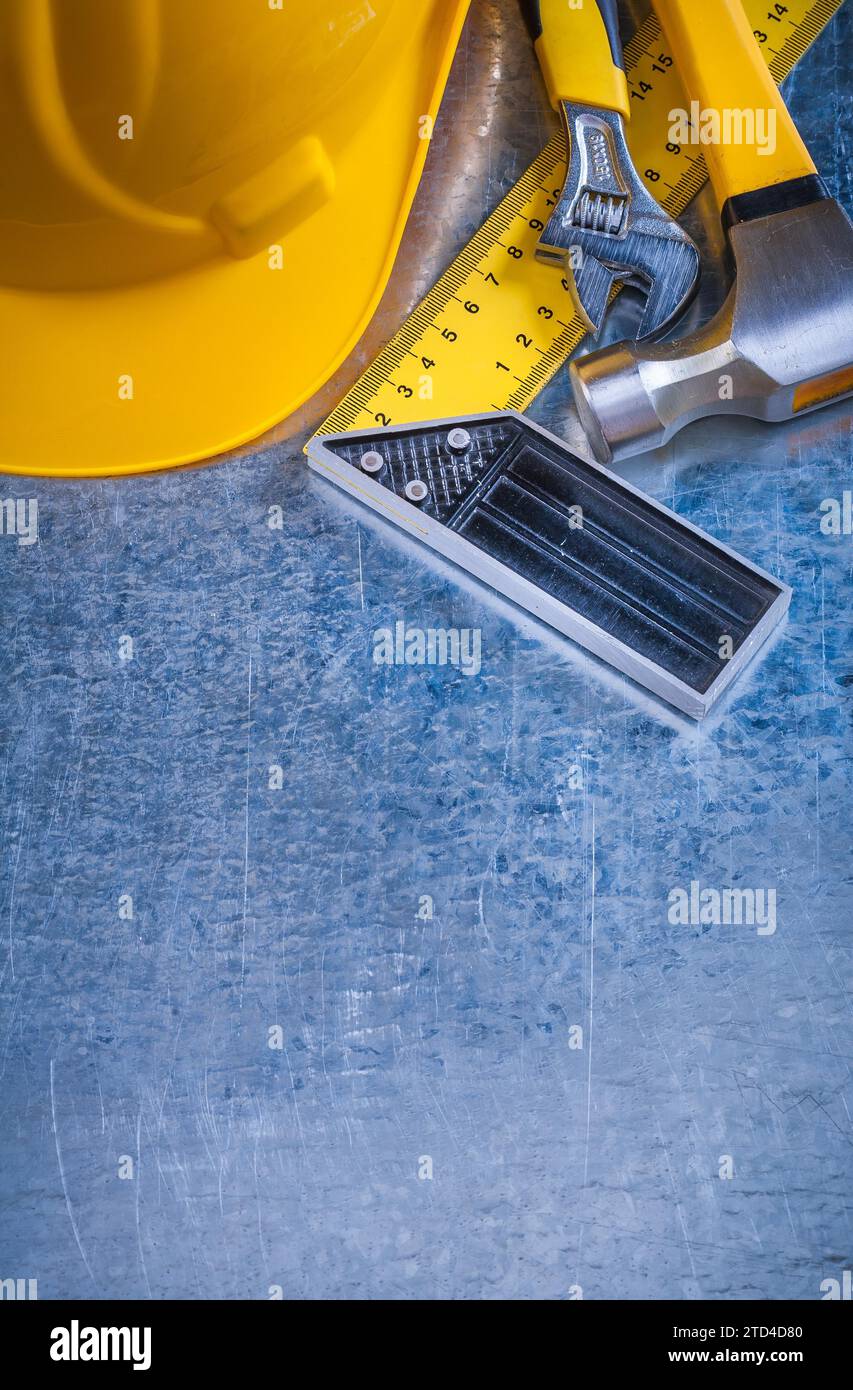 Hard hat claw hammer square ruler and adjustable spanner on scratched