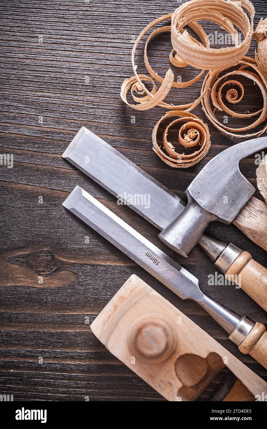 Planner claw hammer flat chisel and wooden curled shavings on vintage wooden board Building concept Stock Photo