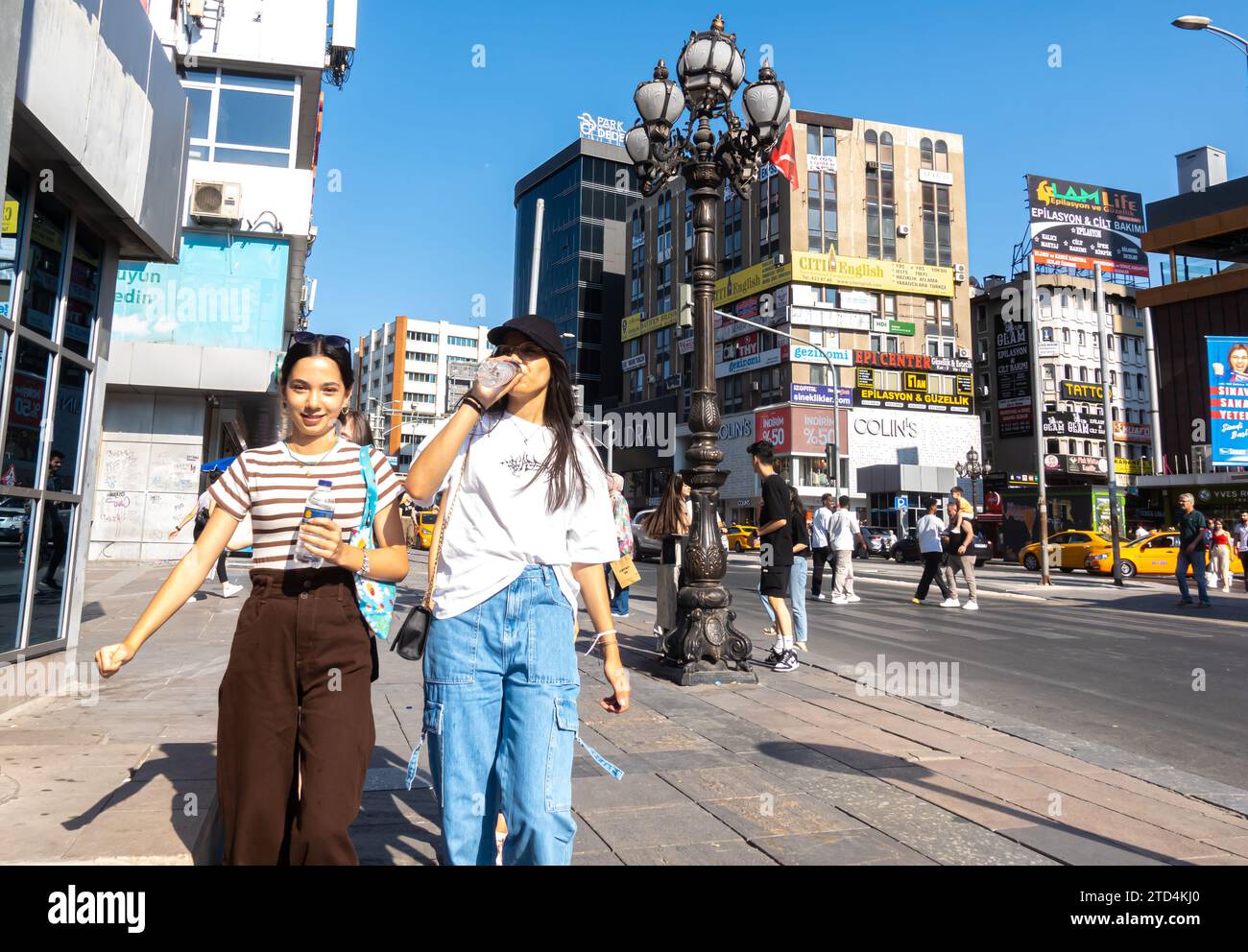 Young Turkish women walk the streets while drinking from a bottle of water, central Ankara Turkey Stock Photo