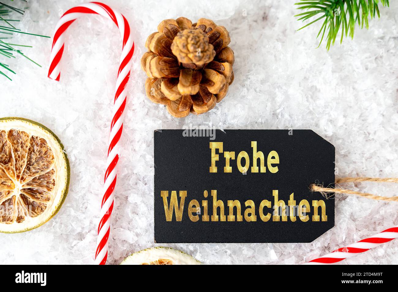 December 15, 2023: Merry Christmas greeting lettering with golden lettering on a sign in front of winter decoration with snow and candy cane. Christmas greeting FOTOMONTAGE *** Frohe Weihnachten Gruß Schriftzug mit goldener Schrift auf einem Schild vor winterlicher Dekoration mit Schnee und Zuckerstange. Weihnachtsgruss FOTOMONTAGE Stock Photo