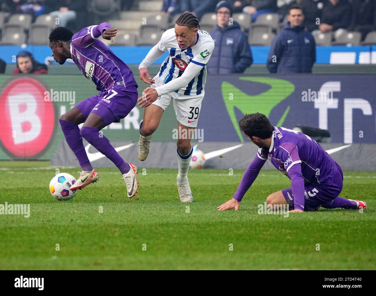 16 December 2023, Berlin: Soccer: Bundesliga 2, Hertha BSC - VfL Osnabrück, Matchday 17, Olympiastadion. Osnabrück's Christian Conteh (l) in action against Hertha's Derry Scherhant (M). Osnabrück's Bashkim Ajdini is on the right. Photo: Soeren Stache/dpa - IMPORTANT NOTE: In accordance with the regulations of the DFL German Football League and the DFB German Football Association, it is prohibited to utilize or have utilized photographs taken in the stadium and/or of the match in the form of sequential images and/or video-like photo series. Stock Photo