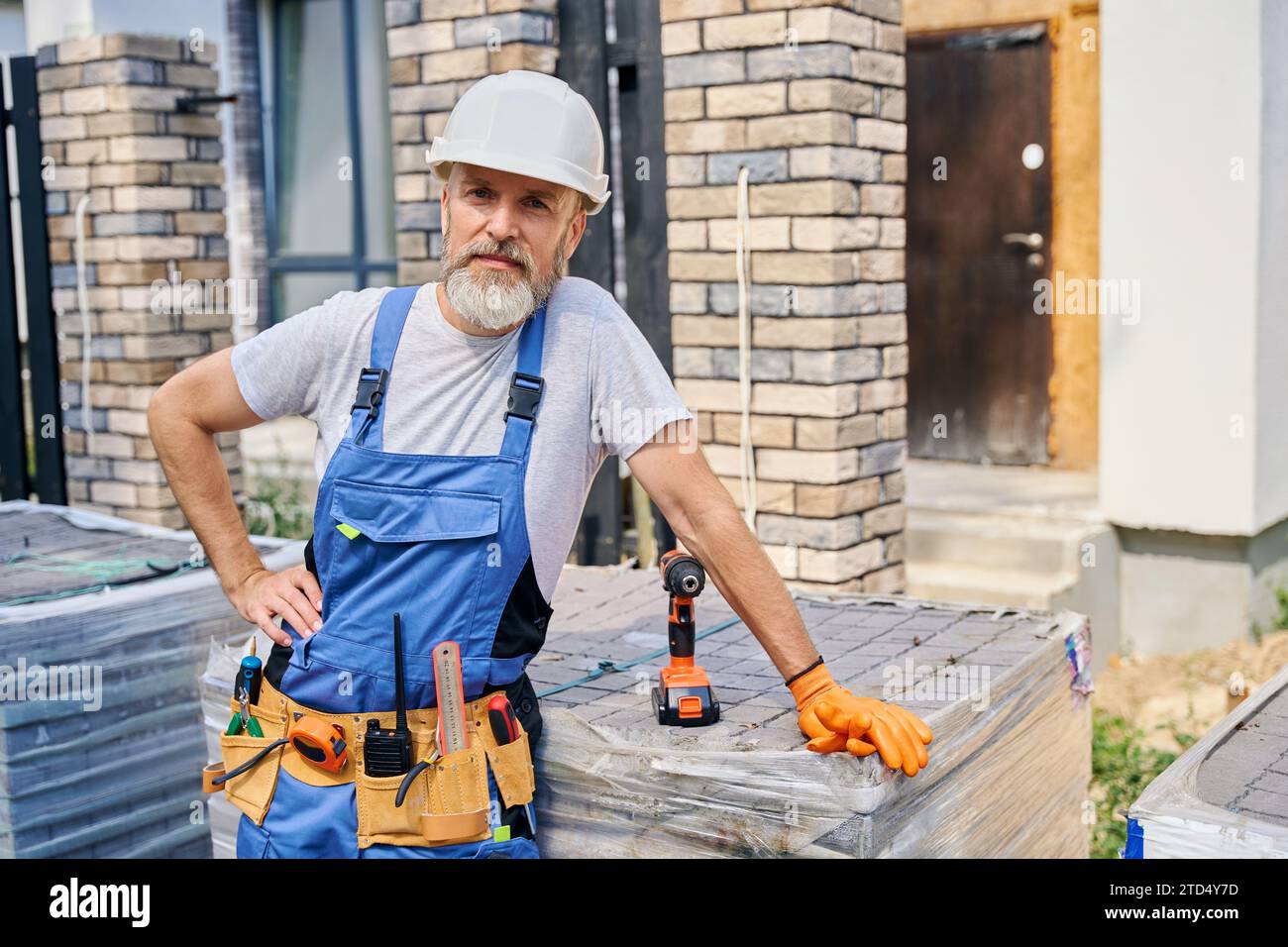 Confident bricklayer posing for camera on construction site Stock Photo ...