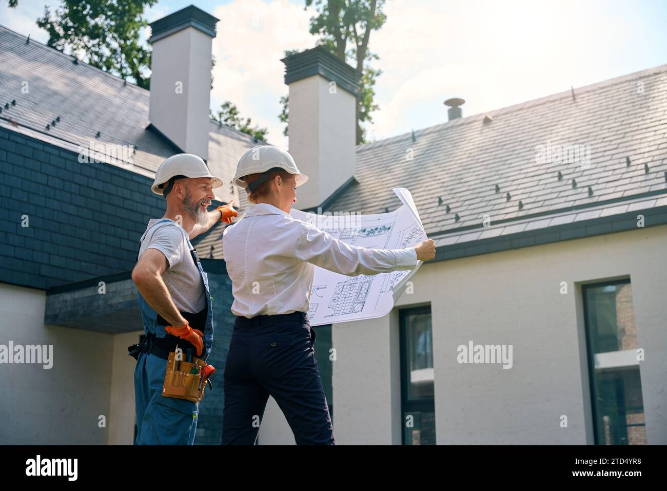 Builder and site supervisor using blueprints during building facade inspection Stock Photo