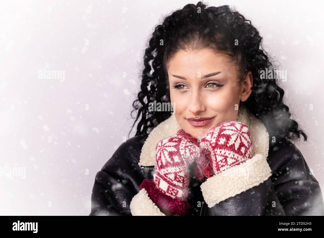 Young, brunette, curly girl in the leather jacket looking like she is freezing. Copy space Stock Photo