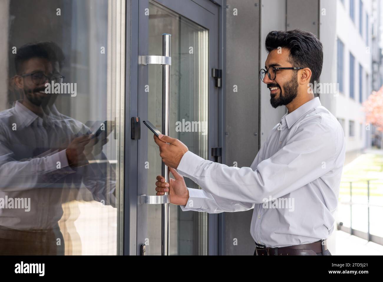 Young businessman using phone to open office door of building, man happy using wireless access, businessman going to work happy smiling. Stock Photo