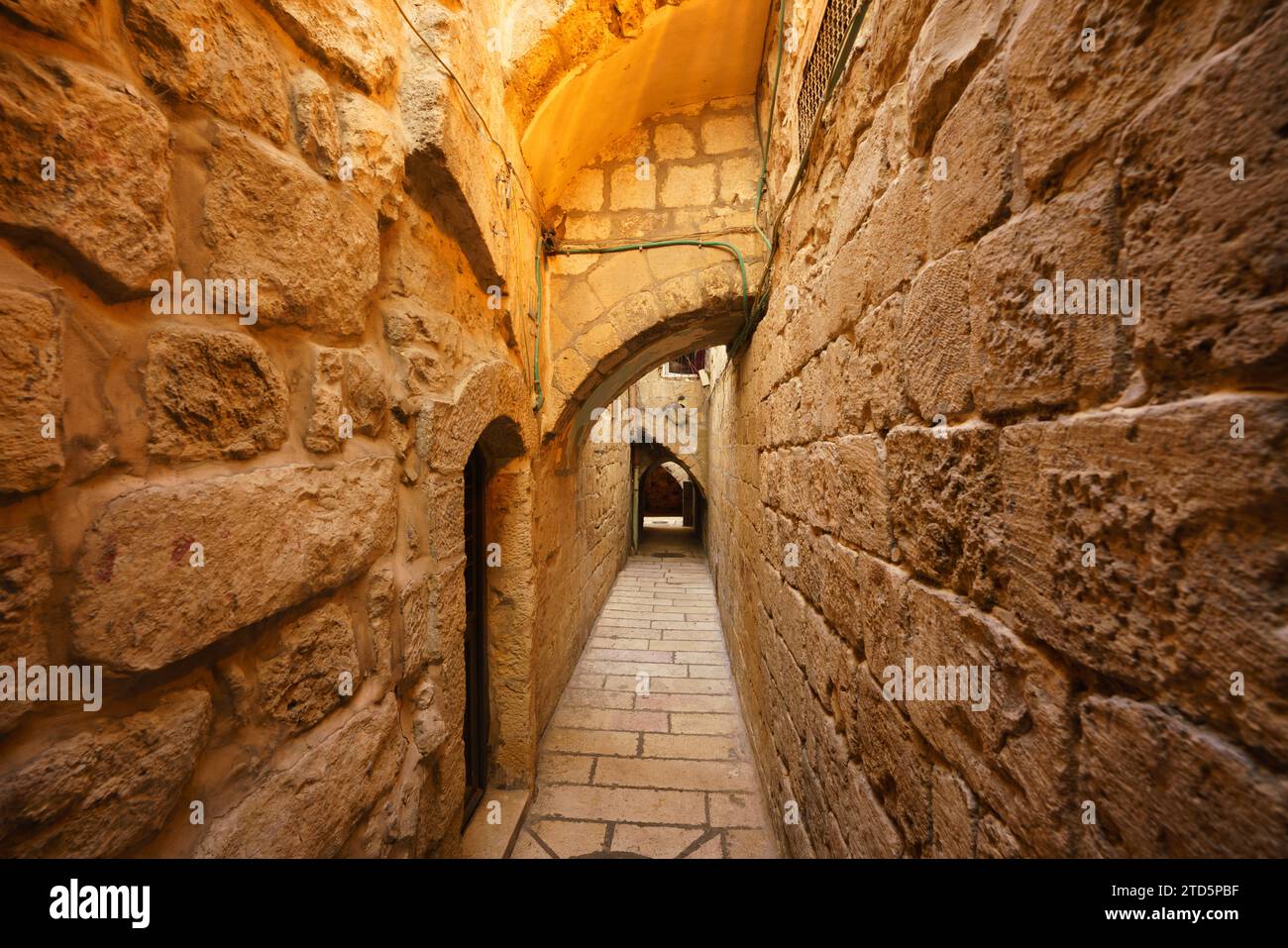 A narrow alley featuring arches and stone walls in the Muslim Quarter of the Old city of Jerusalem Stock Photo