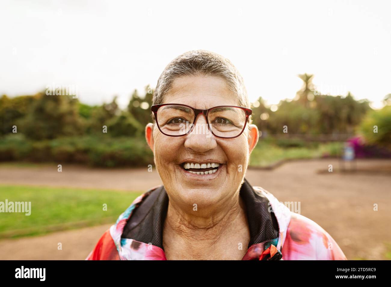 Happy senior woman having fun smiling in front of camera after training activity in a public park Stock Photo