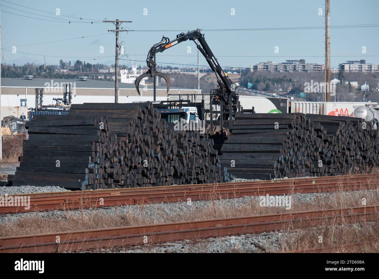 Pile of replacement wooden railroad ties next to tracks, part of renovation on facilities at Halifax Port Stock Photo