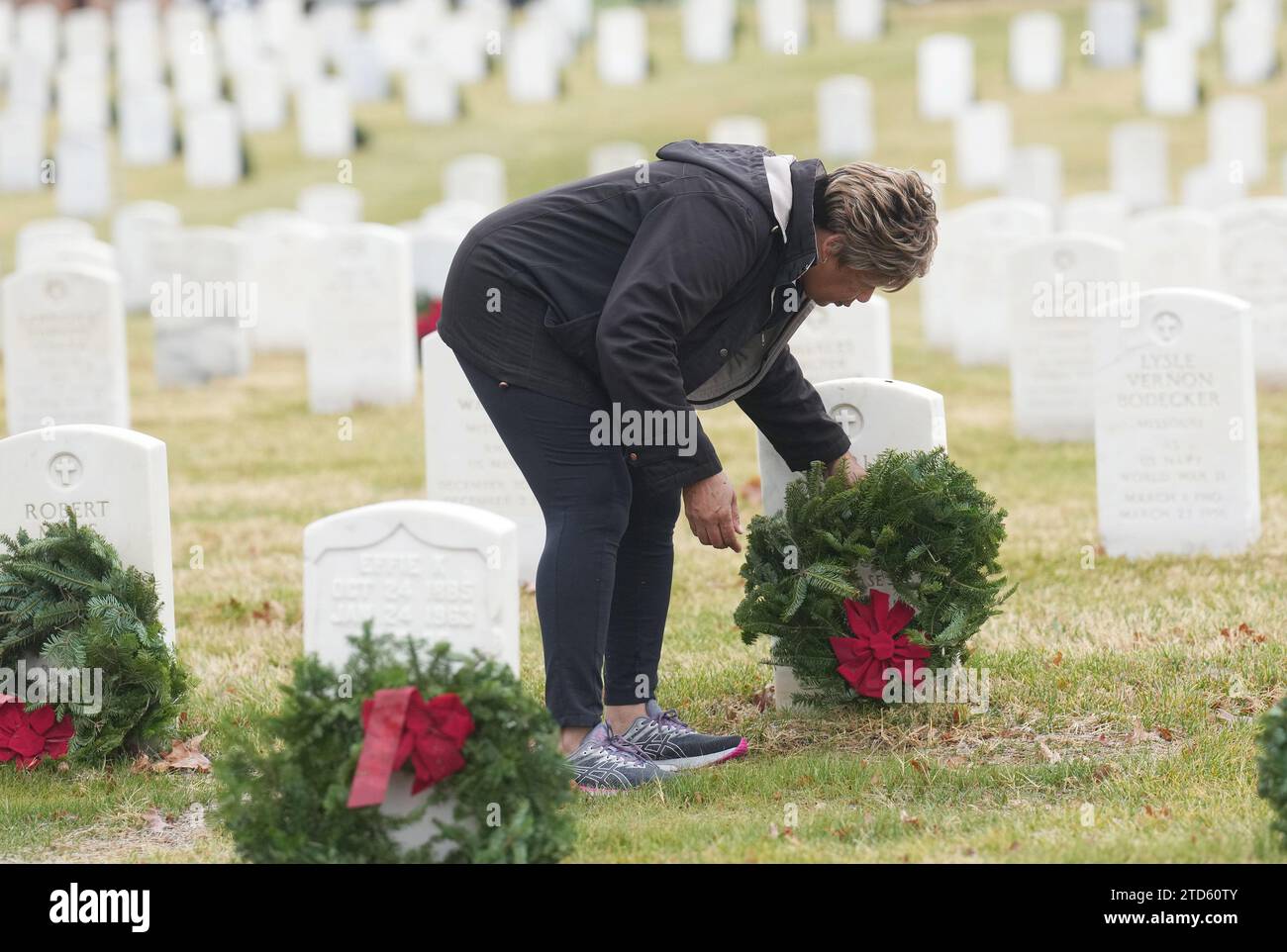 A volunteer places a wreath on a gravesite at Jefferson Barracks