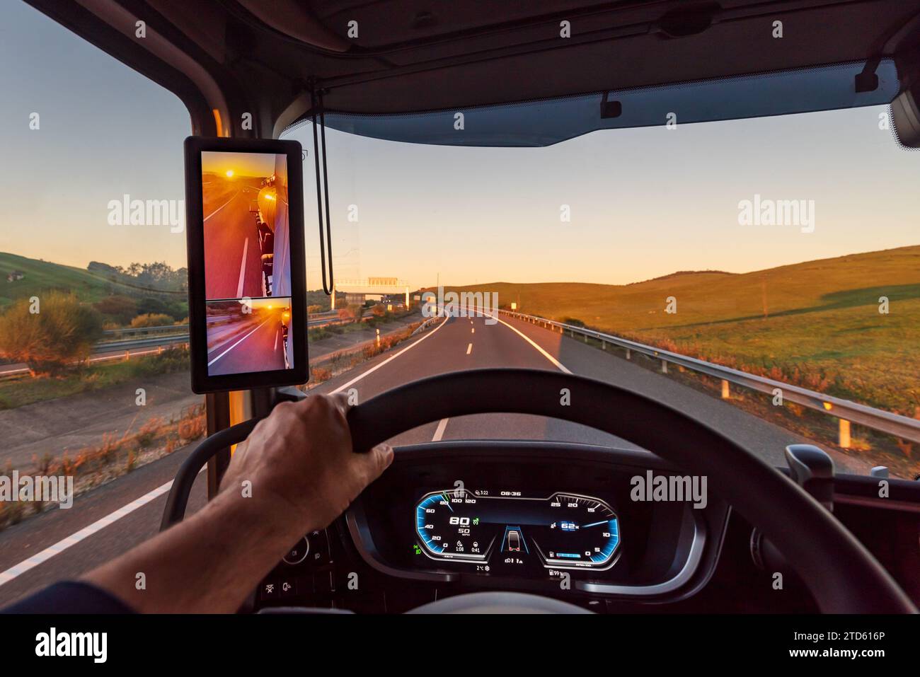 View from inside the cabin of a truck on a highway at dawn, truck with rearview camera. Stock Photo