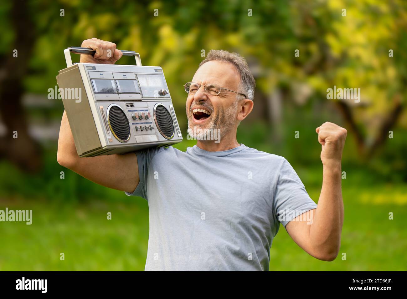 Happy middle aged man listening to retro tape recorder and dancing to his favorite disco song Stock Photo