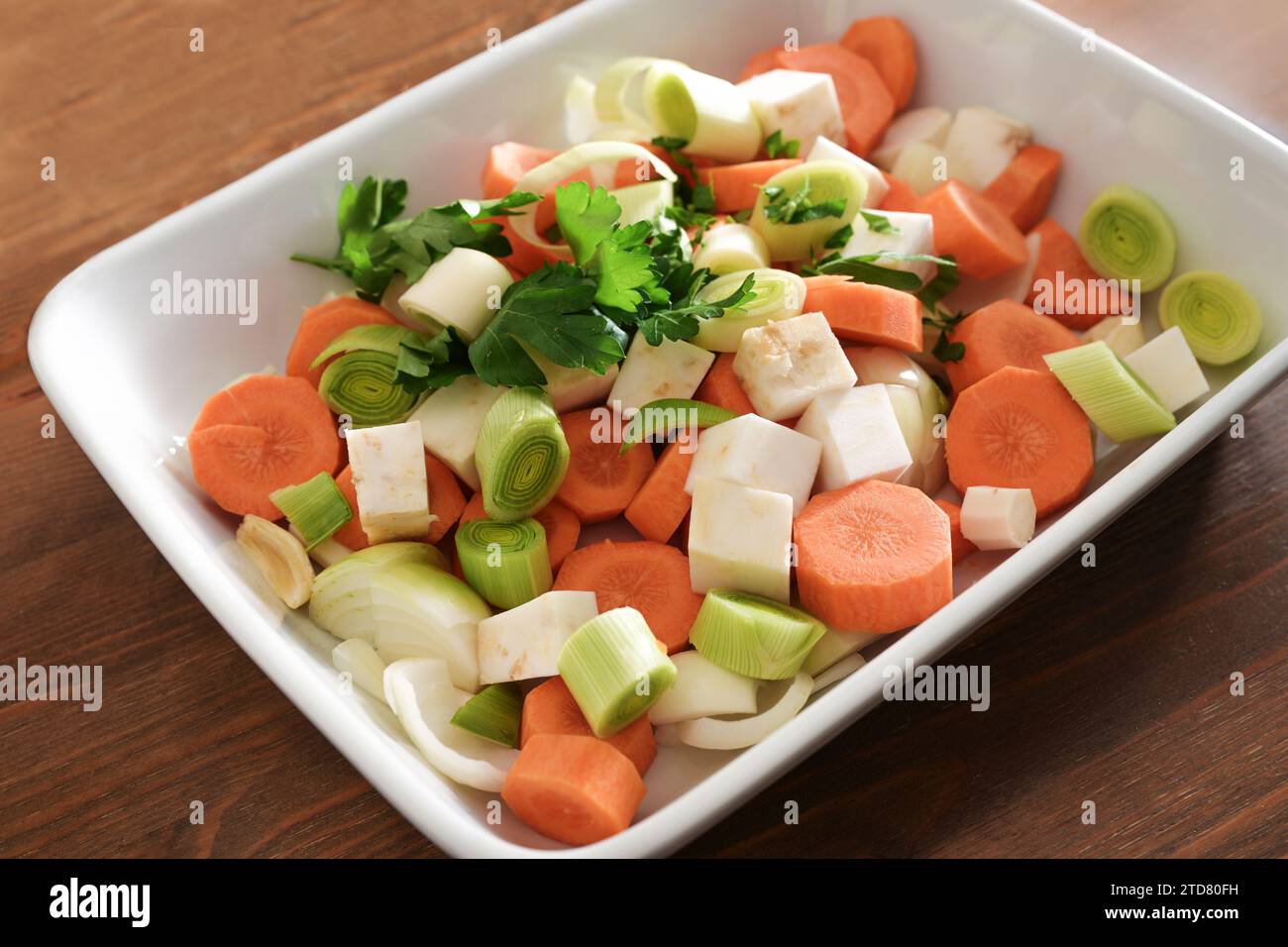 French mirepoix or German Suppengrun (soup greens), raw mixture of diced vegetables with carrots, leek, celery and onion in a white bowl, base for sto Stock Photo