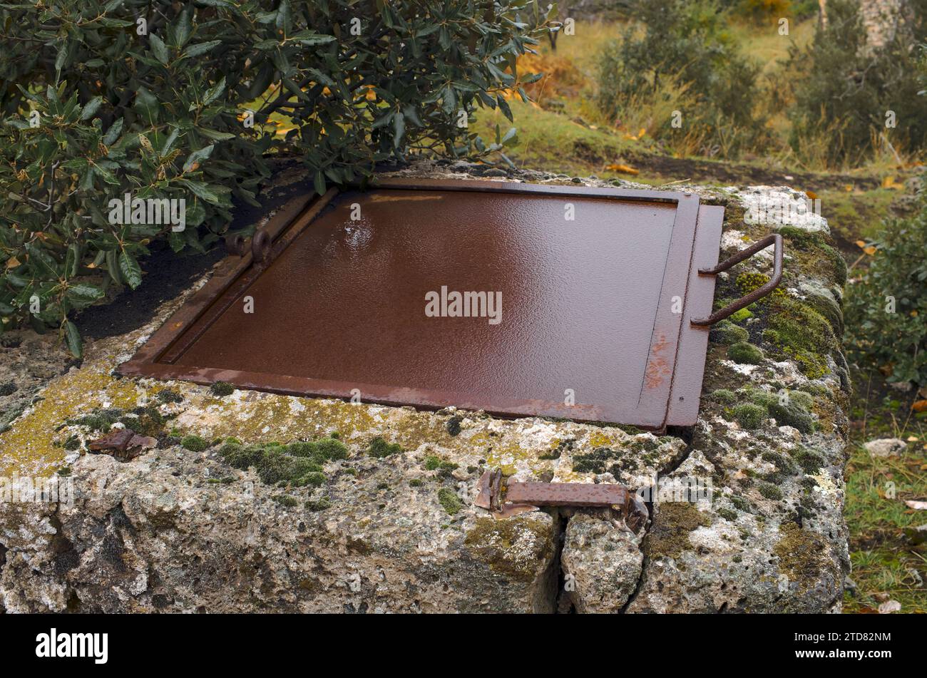 old rusty and wet iron trap door of a water well in the countryside of Etna Park, Sicily, Italy Stock Photo