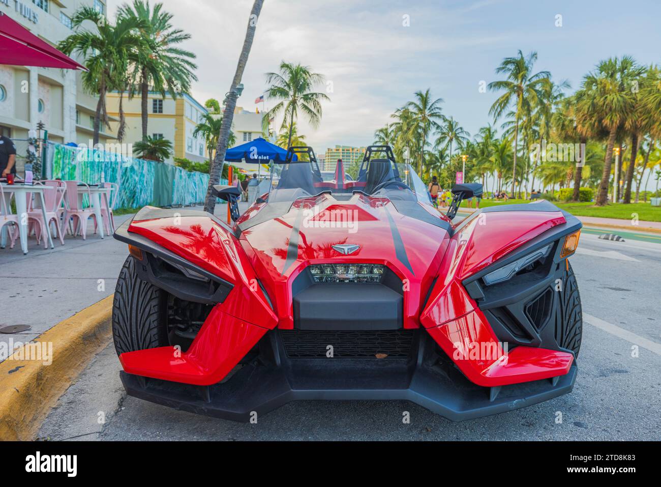 Front view of a parked red Polaris Slingshot on Ocean Drive in Miami