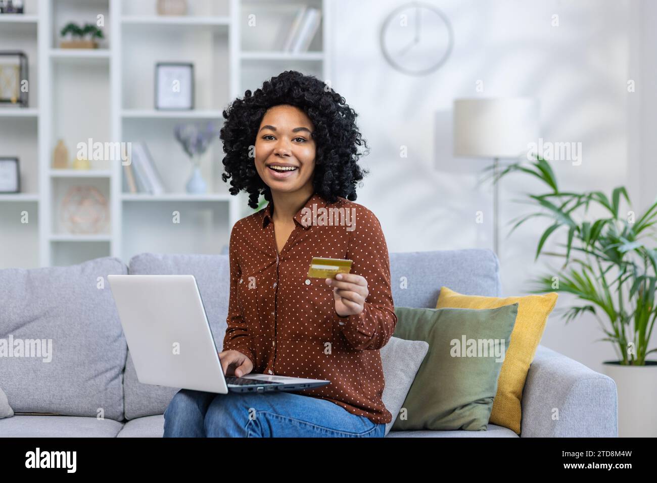 Portrait of a young African American woman sitting on the couch at home ...