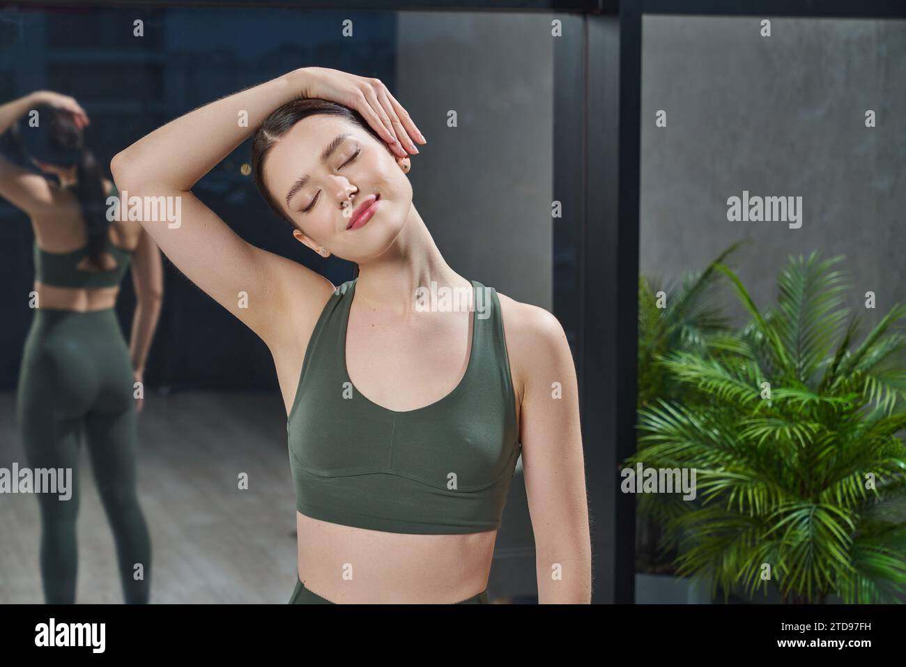 Peaceful woman stretching neck before yoga class. Stock Photo