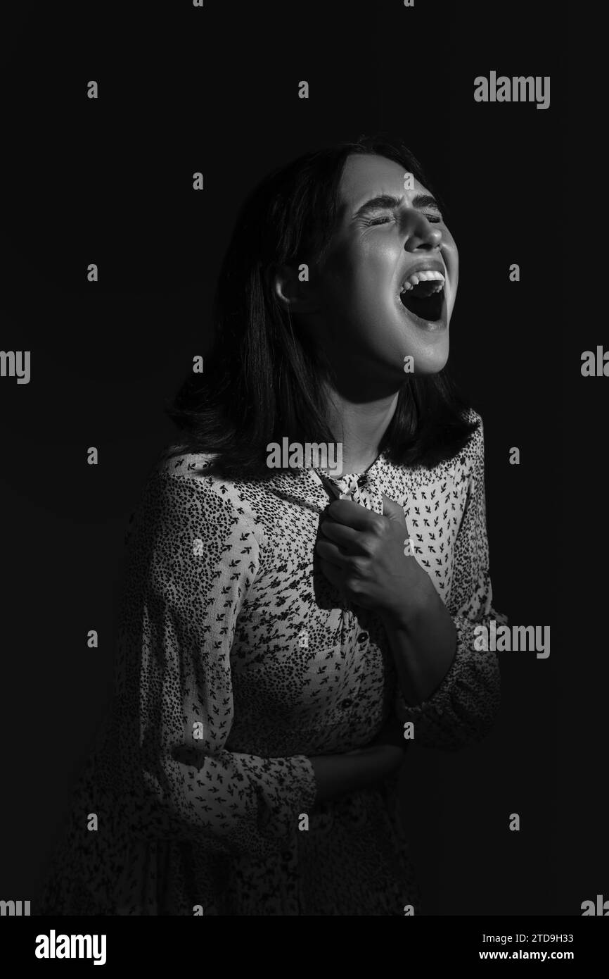 Beautiful young afraid woman screaming on black background Stock Photo