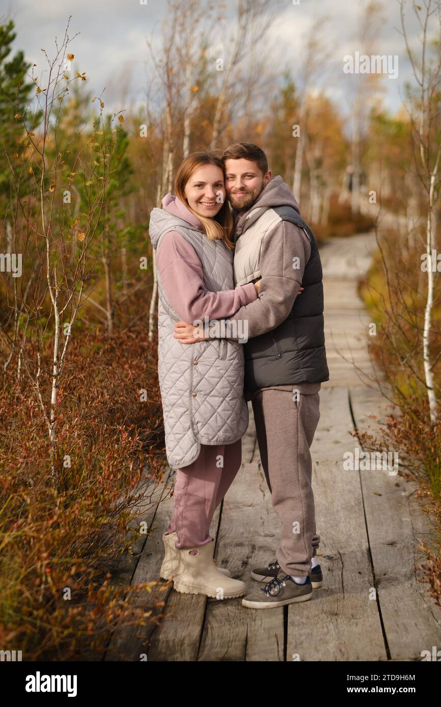 People in boots stand hugging on a wooden path in a swamp in Yelnya ...
