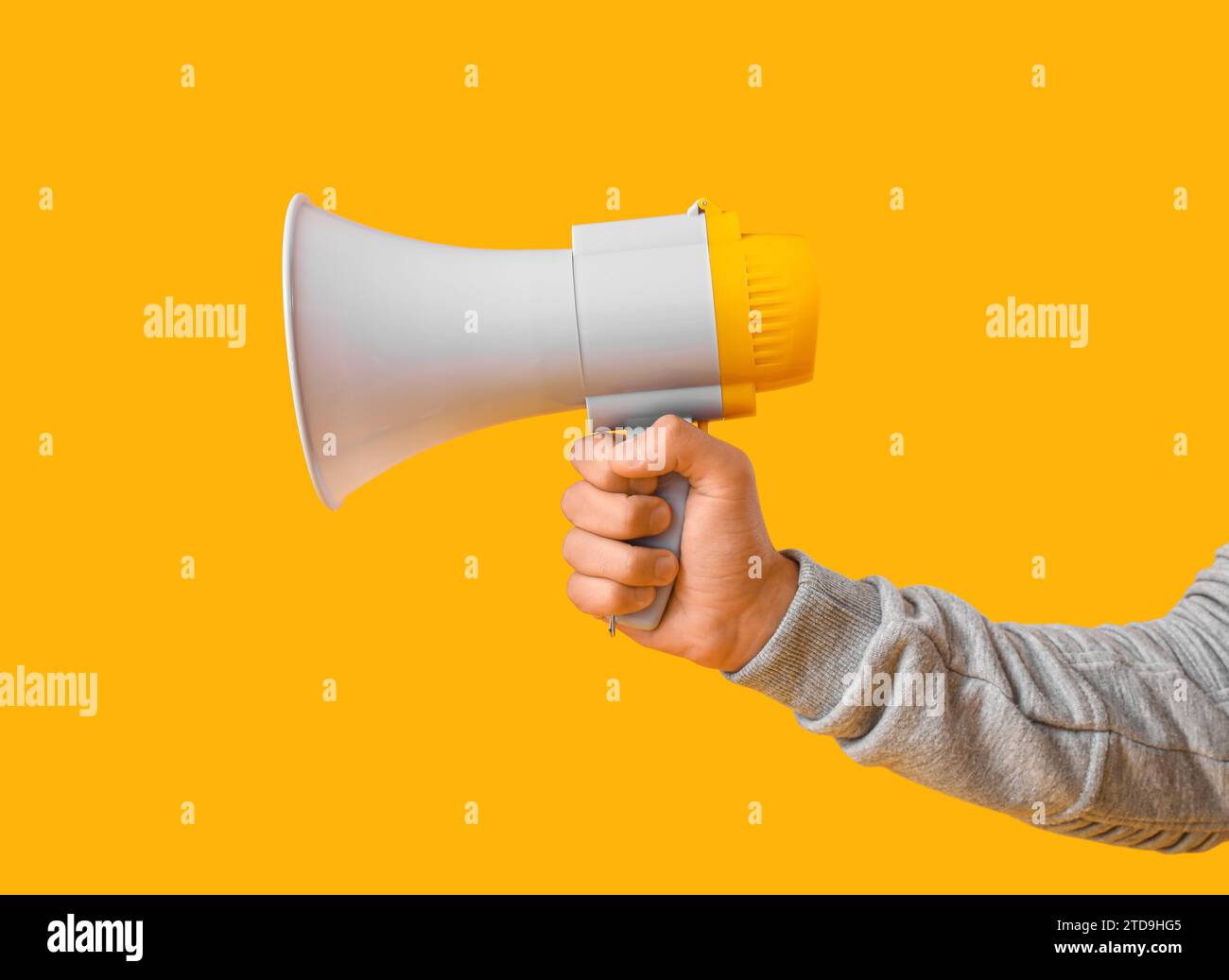 Young man with megaphone on yellow background Stock Photo