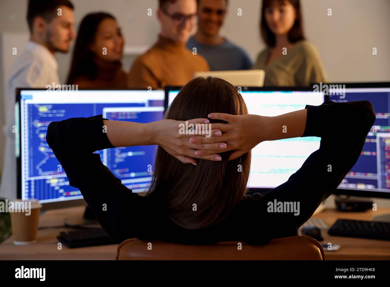 Female programmer working with team at office in evening, back view Stock Photo