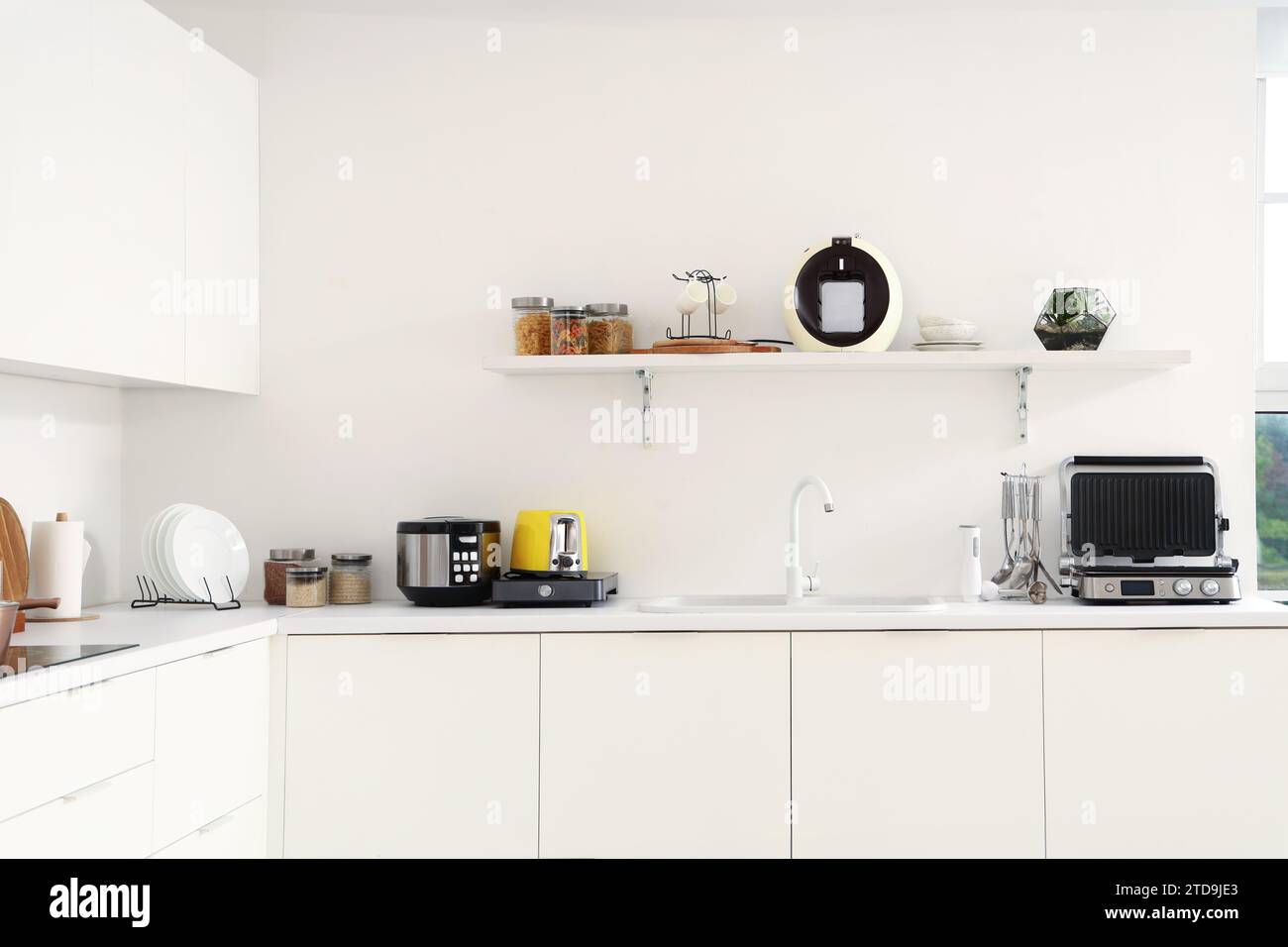 Interior of light kitchen with modern appliances on white counters ...