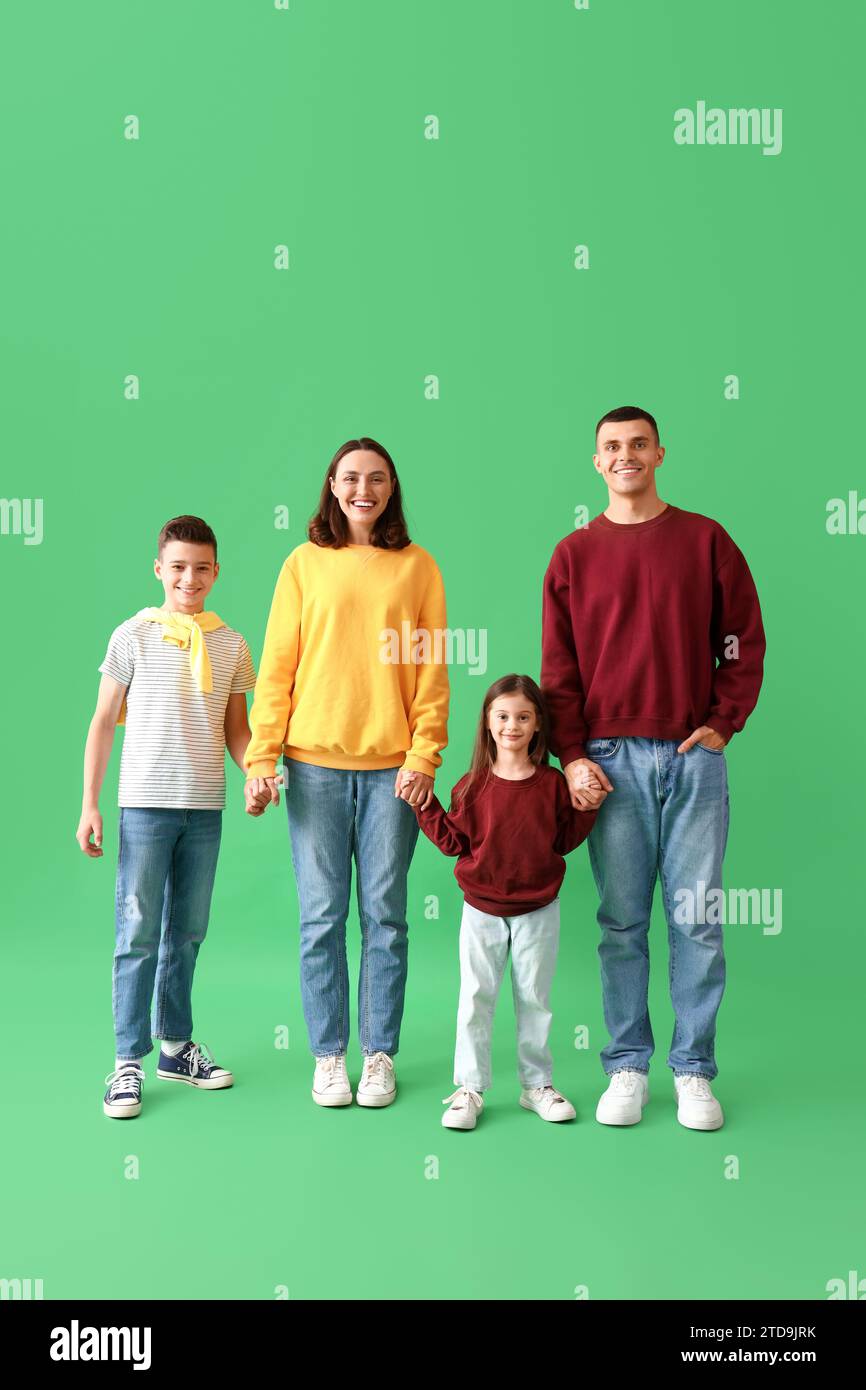 Little children with their parents holding hands on green background Stock Photo