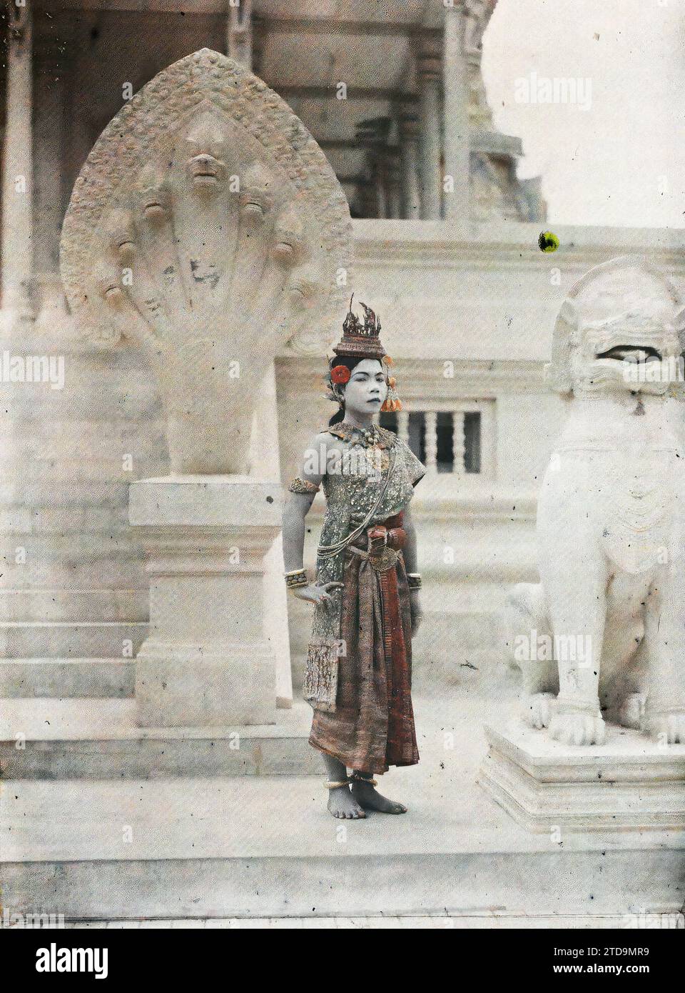 Royal Palace, Phnom Penh, Cambodia, Indochina Royal ballet dancer in 'Mchas Khsatrei' (middle-ranking princess) costume, Human beings, Art, Clothing, Animal, Habitat, Architecture, Woman, Dance, Performance costume, Sacred animal, Costume, Represented animal, fantastic animal, King, Queen, Snake, Staircase, Makeup, Sculpture, Portrait, Accessory, Flower, Lion, Jewel, Sculpted decor, Palace, Castle, Indochina, Actress, Phnom Penh, 01/01/1921 - 31/12/1921, Busy, Léon, Léon Busy photographer en Indochine, Autochrome, photo, Glass, Autochrome, photo, Positive, Vertical Stock Photo