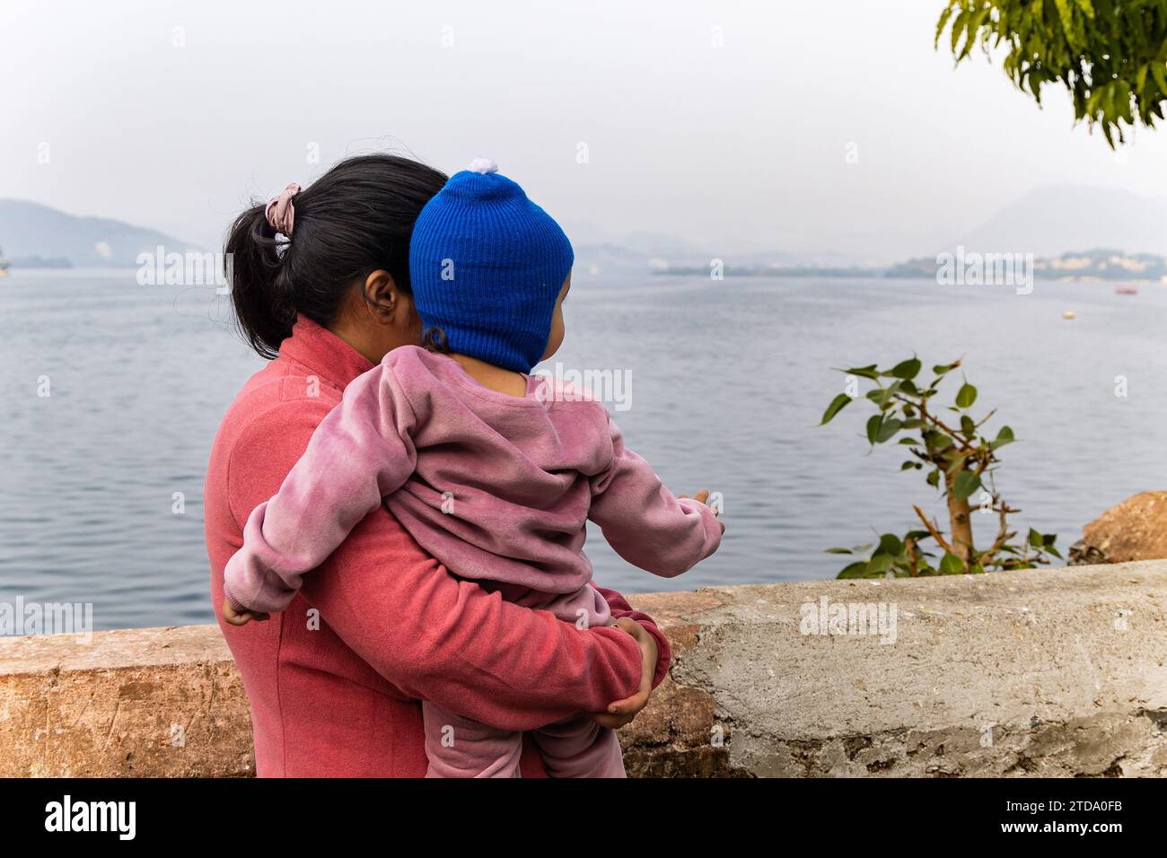 young mother with her son looking at mountain lake landscape at morning image is taken at Jagdish Temple udaipur rajasthan india. Stock Photo