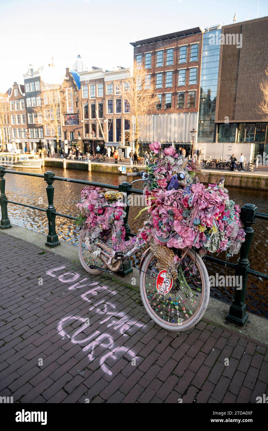 Amsterdam The Netherlands 17th December 2023 Anne Frank House on the Prinsengracht. On the canal in front a brightly coloured decorated pink bike is parked with the message. Love is the cure Anne Frankhuis, versierde, fiets, rose, Stock Photo