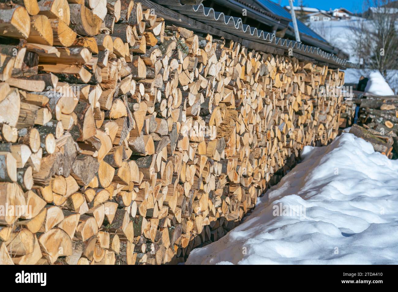 Firewood storage for the winter under a shed outside in a snowy winter place. Stock Photo