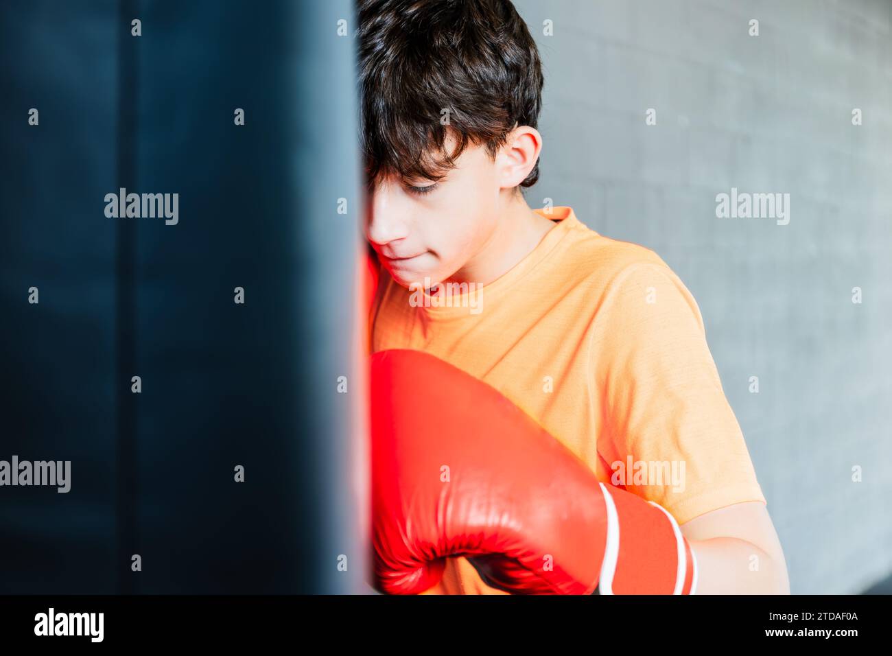 Horizontal photo caucasian teen boy with orange tshirt and red boxing