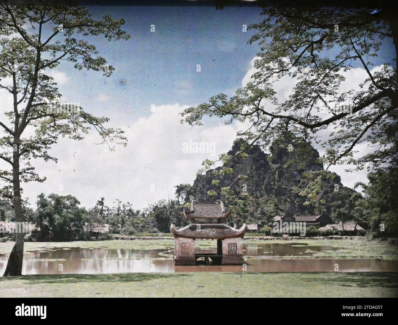 Province of So' n-tâi, Tonkin, Indochina Pagodon of the Thay pagoda also known as the 'Heavenly Bliss' (Thien Phuc), located at the foot of the Sai-so' n limestone reef, Nature, Environment, Religion, Art, Habitat, Architecture, Landscape, Buddhism, Mount, mountain, Temple, Roof, Lake, pond, Puppet, Theater, Religious architecture, Indochina, Tonkin, Phuquoc vai, View taken in the opposite direction (towards the East), Son-Tai [région], 14/05/1916 - 14/05/1916, Busy, Léon, Léon Busy photographer en Indochine, Autochrome, photo, Glass, Autochrome, photo, Positive, Horizontal, Size 9 x 12 cm Stock Photo